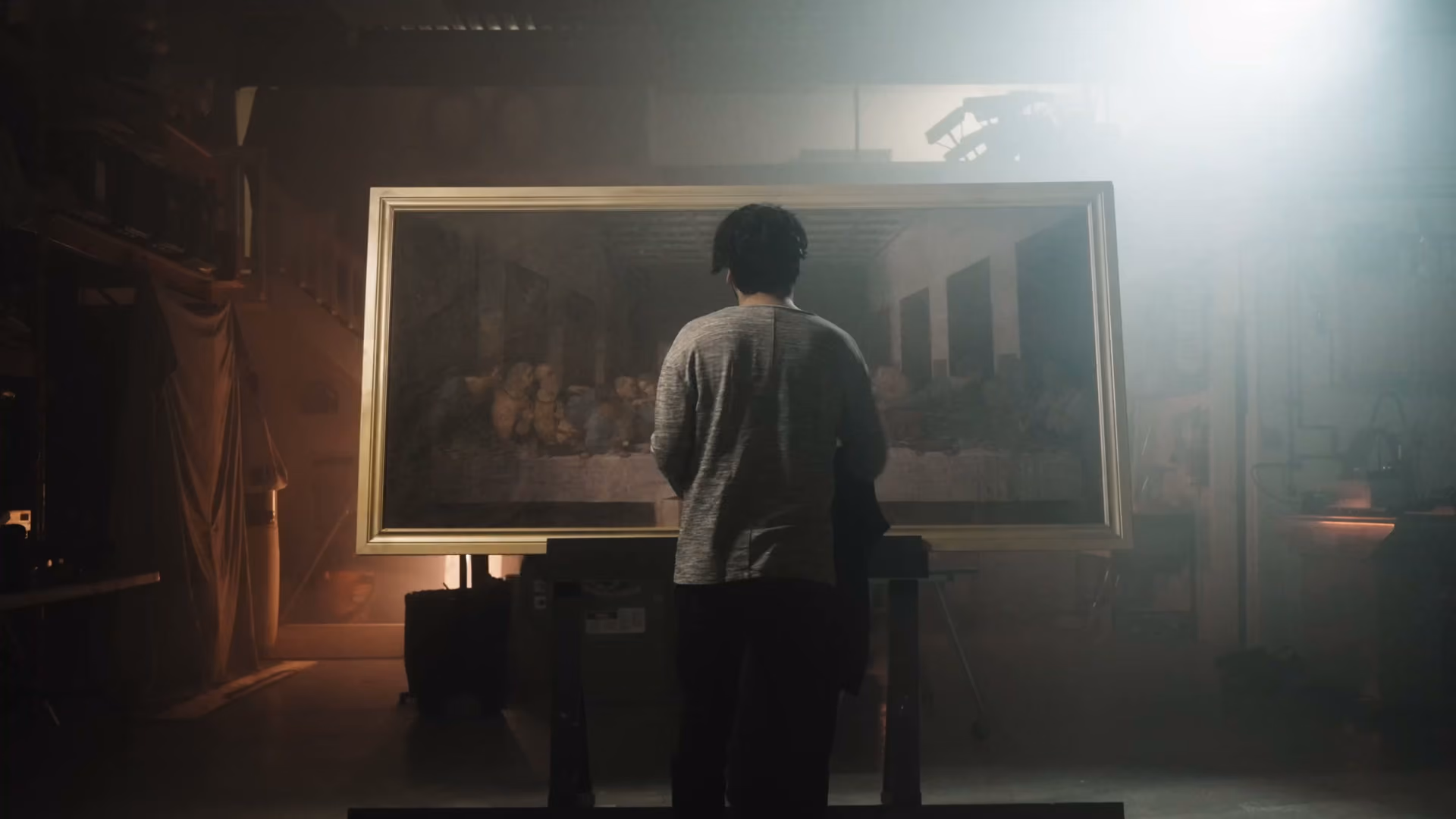 A person standing before a large illuminated painting in a darkened gallery.